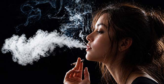 Woman exhaling smoke or vapor against a dark background